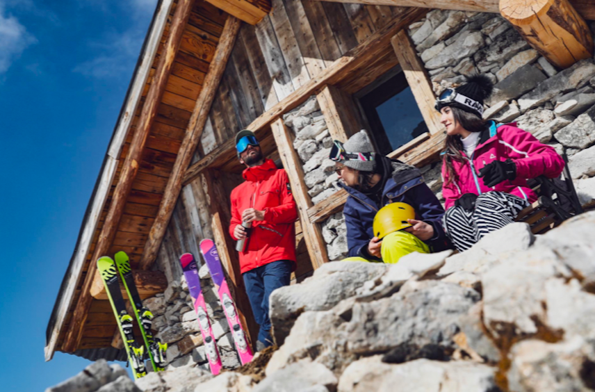 Groupe d'amis devant un refuge à la montagne avec leurs skis