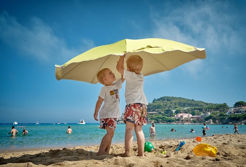 Deux enfants sur une plage sous un parasol
