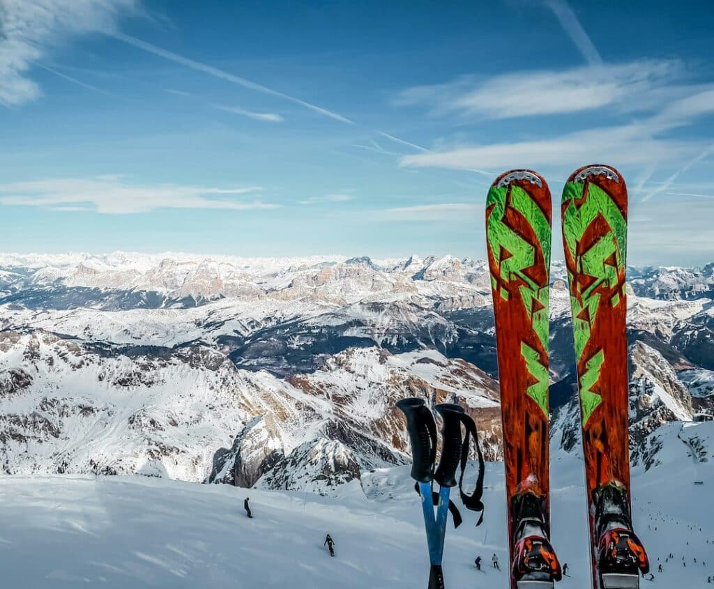 Skis plantés dans la neige avec piste de ski en contrebas